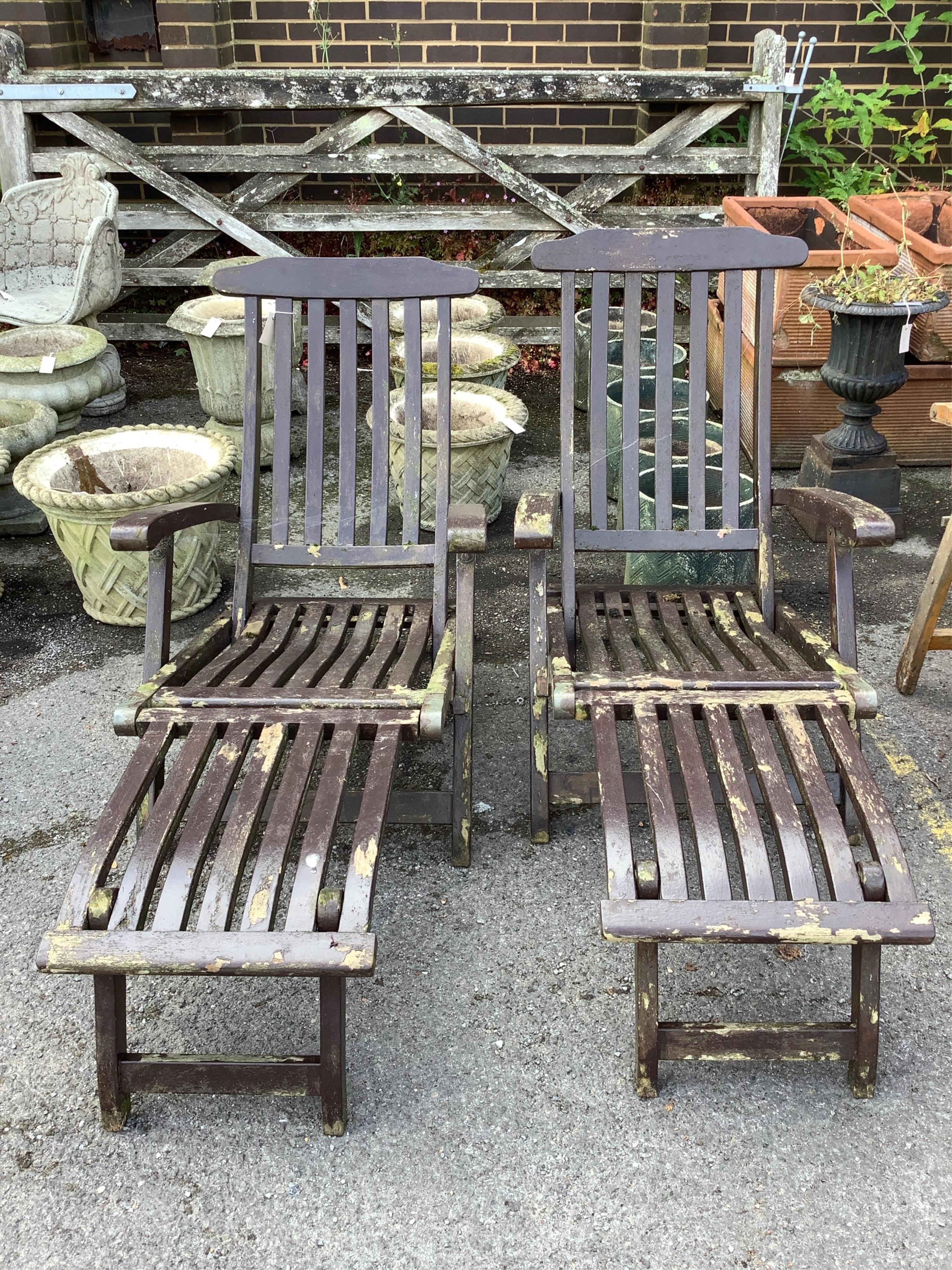 A pair of stained teak garden steamer chairs. Condition - fair
